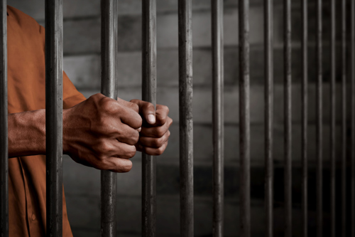 a person in prison and holding onto the bars